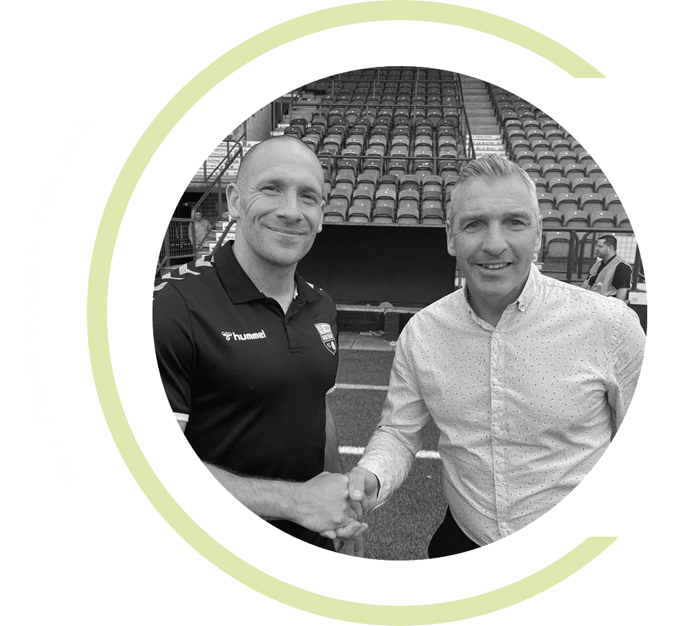 Two men shaking hands in front of a stadium.